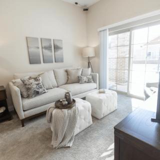 A bright and modern living room with a stylish sofa, coffee table, and decorative accessories, enhanced by natural light from large windows.