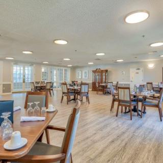 An empty dining area with neatly arranged tables and chairs, well-lit by natural light.