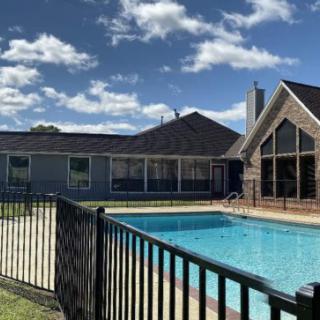 A residential home with a sunny backyard featuring a swimming pool and surrounding fence.