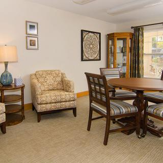 A cozy living room with a round dining table, armchair, and elegant decor.