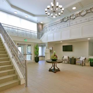 A modern and spacious lobby with a grand staircase, elegant chandelier, and comfortable seating area.
