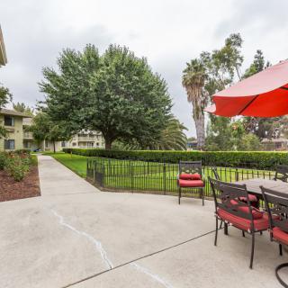A peaceful outdoor patio area with seating, an umbrella, and a view of a tree-lined landscape.