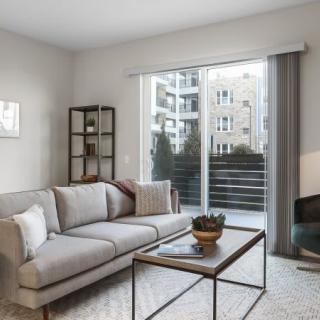 A modern living room with a comfortable sofa, coffee table, and large window overlooking an urban setting.