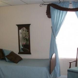 A simple bedroom with blue curtains and matching bedspread.
