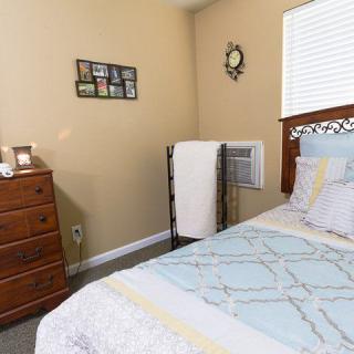 Cozy bedroom interior with a neatly made bed and wooden furniture.