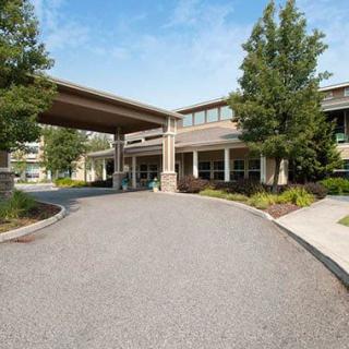 A building entrance with a covered driveway and landscaped surroundings.