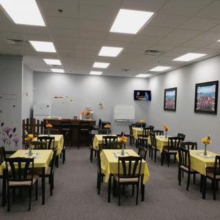 An indoor dining area with tables covered in yellow tablecloths, arranged in a neatly organized layout.