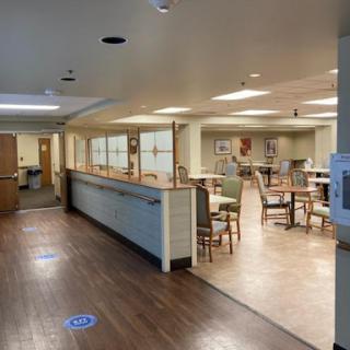 A spacious interior view of a dining area in a health facility, featuring tables and chairs arranged for usage.