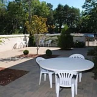 An outdoor patio area with a white plastic table and chairs surrounded by greenery.