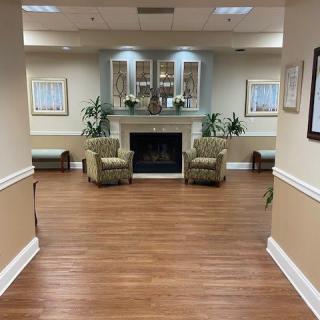 A cozy lobby area with chairs and a fireplace, decorated with plants and artwork.