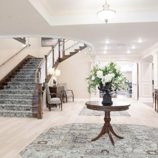 Elegant foyer with a central table adorned with flowers and a grand staircase.