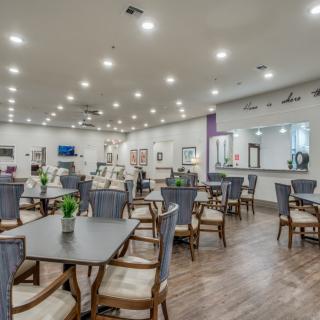 A modern dining area with neatly arranged tables and chairs, illuminated by bright overhead lights.