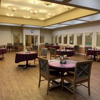 An empty dining area with neatly arranged tables and chairs under warm lighting.
