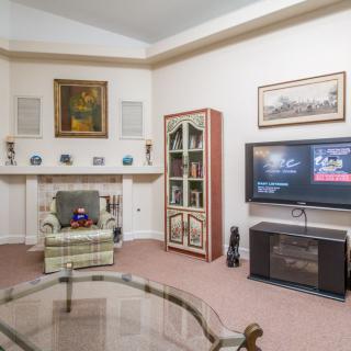 A cozy living room with a TV, fireplace, armchair, and various decorations.