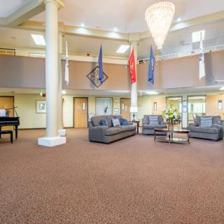 A spacious lobby area with sofas and flags displayed, featuring a large chandelier and carpeted flooring.