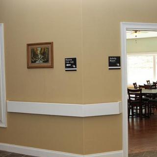 A hallway with a view into a dining room, featuring wall signage and a framed painting.