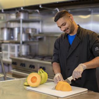 A chef skillfully slicing a cantaloupe in a modern kitchen.