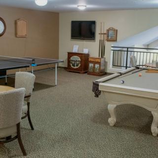 A spacious game room featuring a pool table and ping pong table alongside comfortable seating options.