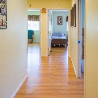 A well-lit hallway leading to a room with a hospital bed.
