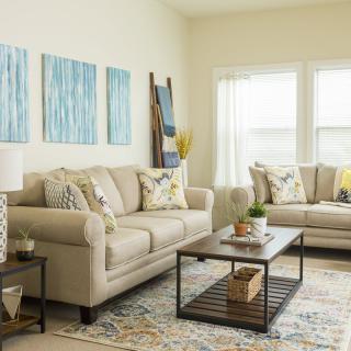 A cozy living room featuring beige sofas, a wooden coffee table, and abstract artwork on the wall.