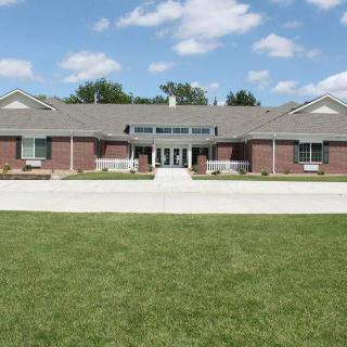 A brick building with a well-maintained lawn under a partly cloudy sky.
