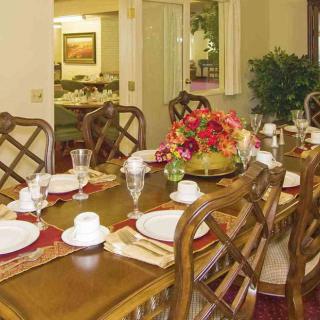 A beautifully set dining table with elegant plates, cups, and a floral centerpiece.