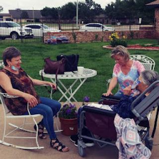 Three women enjoying a sunny day outdoors, engaging in conversation and companionship.