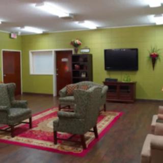 A cozy living room with a green wall, comfortable seating, and a television.