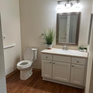 A clean and modern bathroom with a toilet, sink, and mirror.