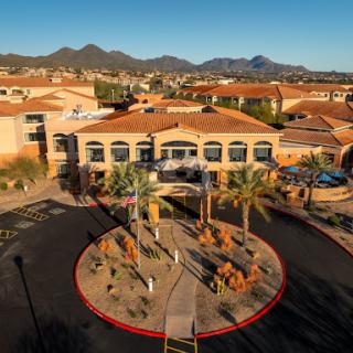 Aerial view of a resort surrounded by mountains and palm trees in Arizona, showcasing vibrant architecture under clear skies.