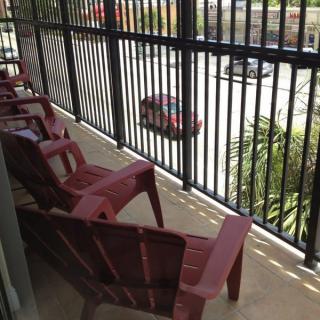 A balcony with red chairs overlooking a street.