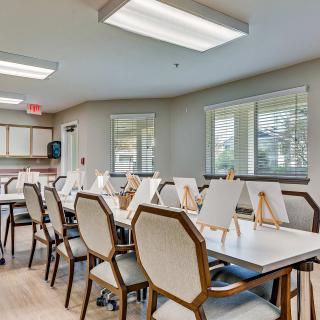 An art classroom equipped with tables, chairs, and easels, well-lit by natural and artificial lighting.