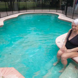 A woman relaxing by the edge of a swimming pool.