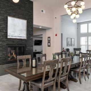A modern dining room with a large table, chairs, and a stylish chandelier.