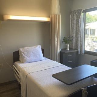 A clean and organized hospital room with a single patient bed by a window.