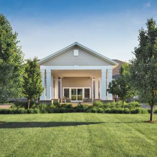 A beautiful residential house with a well-maintained lawn and surrounding trees.