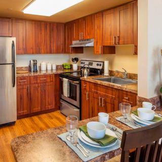 A modern kitchen with wood cabinets, stainless steel appliances, and a neatly set dining table.