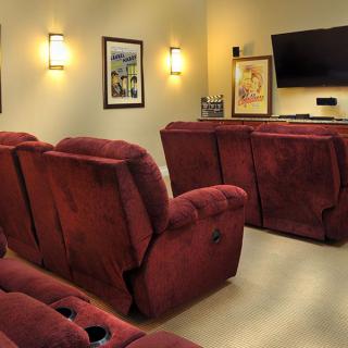 Cozy home theater setup with red recliner chairs and a mounted television.