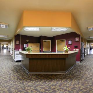 A spacious office lobby with a central reception desk and hallways extending to the sides.