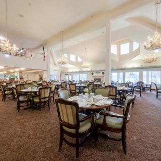 An elegant and spacious dining area with neatly arranged tables and chairs, illuminated by chandeliers.