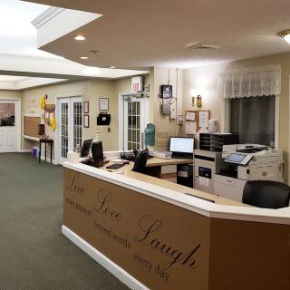 A well-lit office reception area with a desk, computers, and a printer.