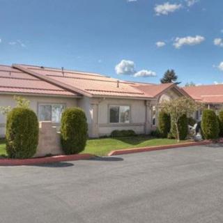 A single-story residential building with a well-maintained front yard and a clear blue sky.