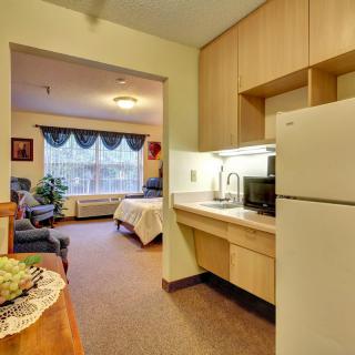 A cozy apartment interior featuring a compact kitchen adjacent to a furnished living area and bedroom.