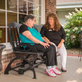 A caregiver engaging in a heartfelt conversation with a senior resident on a sunny day.