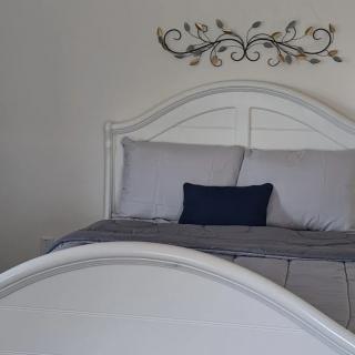 A neatly made bed with gray bedding and decorative wall art above it.
