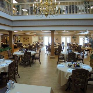 A spacious dining hall with elegantly arranged tables and a chandelier.