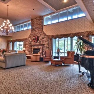 A spacious and elegantly decorated living room with a grand piano, large fireplace, and comfortable seating.