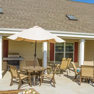 A cozy patio setup with chairs, a table, and an umbrella beside a barbecue grill.