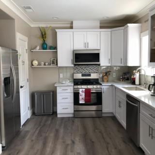 A modern kitchen with white cabinets, stainless steel appliances, and hardwood flooring.
