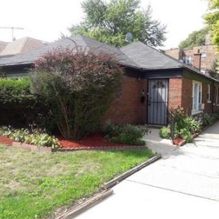 A brick house with a landscaped front yard and driveway.